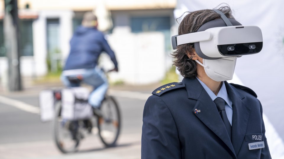 Eine Polizistin mit Virtual-Reality-Brille, im Hintergrund eine Radfahrerin