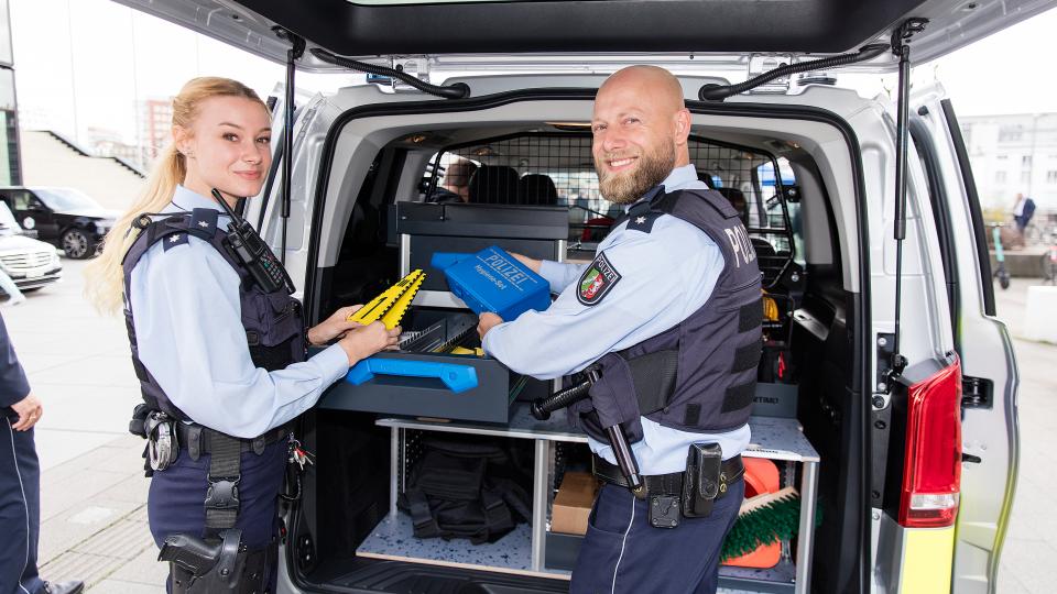 Neue Streifenwagen für die Polizei - Polizistin und Polizist am Heck des Autos
