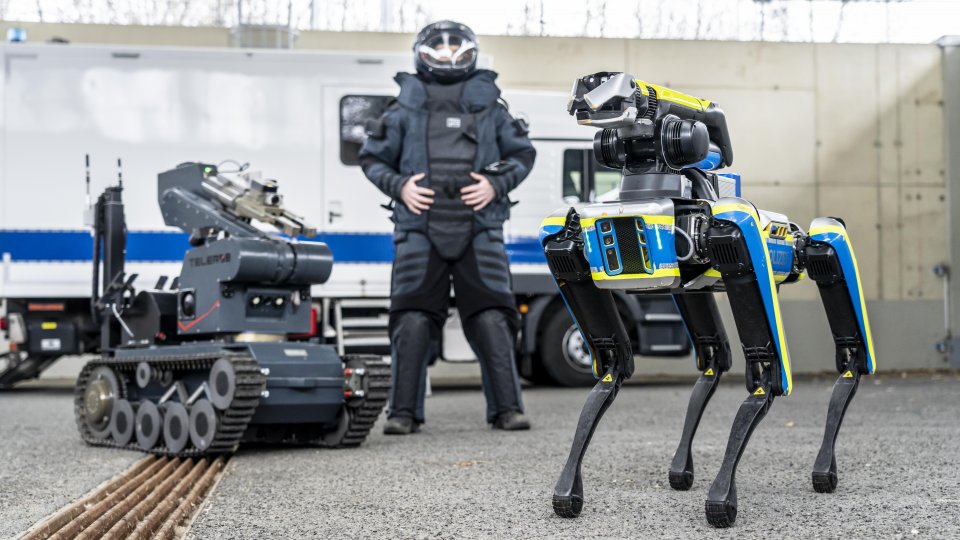 Landeskriminalamt NRW testet Roboterhund Spot bei Sprengstoffentschärfung, Polizist mit Schutzkleidung, Roboter und Roboterhund