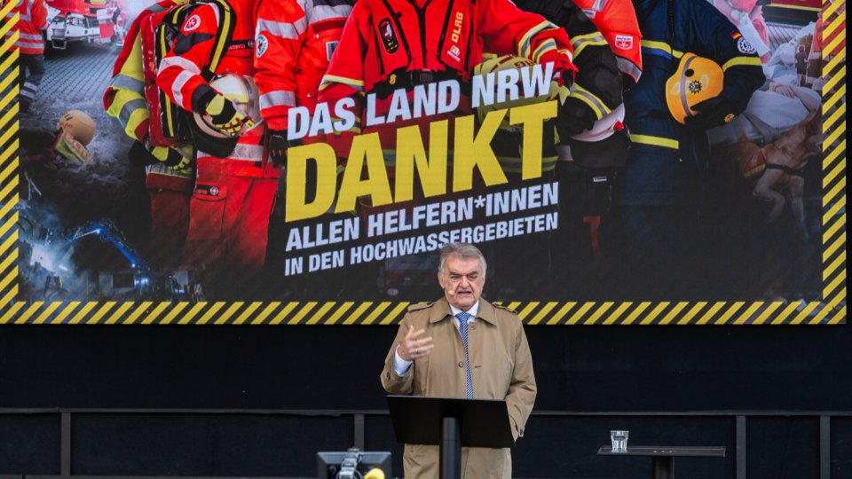 MInister Reul auf Bühne vor Plakat "Das Land NRW dankt"