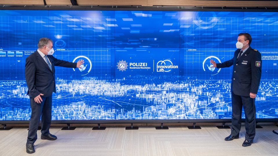 Eröffnung Innovation Lab Polizei 19.01.2022 - Minister Reul mit Projektleiter vor Videowand