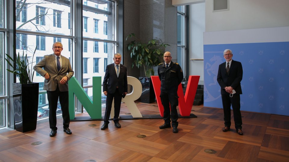 Vertreter der Kompetenzteams mit Minister Reul vor NRW-Buchstaben