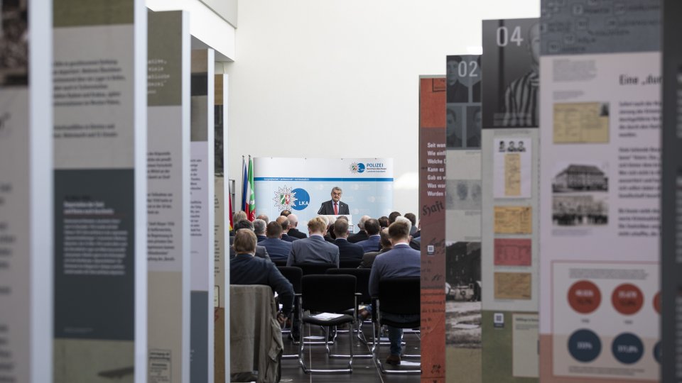 Minister Reul im Hintergrund einer Ausstellung 