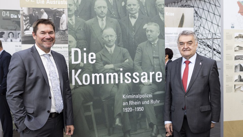 Ingo Wünsch und Herbert Reul neben Aufsteller "Die Kommissare"
