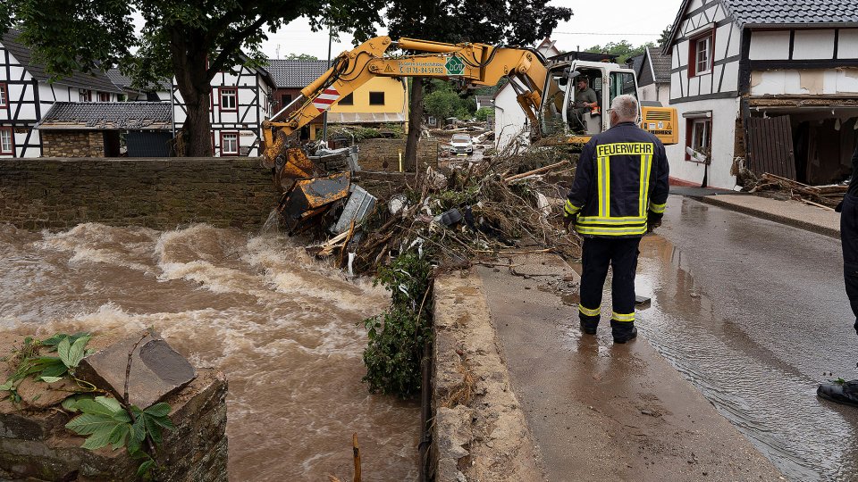 Starkregen - Feuerwehrmann und Bagger beim Aufräumen