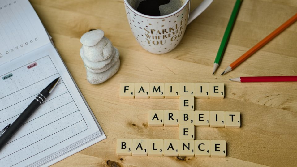 Work-Life-Balance, Schreibtisch mit Stiften, Kaffee und Buchstaben-Steinen