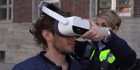 Ein Verkehrsteilnehmer bekommt von einer Polizistin die Virtual Realitiy Brille aufgesetzt